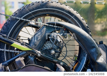 Broken electric bicycle with pulled out inner tube and flat rear tire 142345008