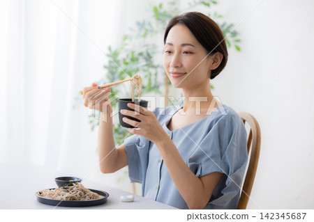A woman eating soba noodles 142345687