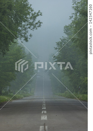 A view of the straight road shrouded in mist, seen from the starting point of the "Road to Heaven" in Shari Town, Hokkaido, Japan. A view of the straight road shrouded in mist, seen from the starting point of the "Road to Heaven" in Shari Town, Hokkaido, Japan. 142347160