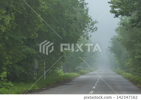 A view of the straight road shrouded in mist, seen from the starting point of the "Road to Heaven" in Shari Town, Hokkaido, Japan. A view of the straight road shrouded in mist, seen from the starting point of the "Road to Heaven" in Shari Town, Hokkaido, Japan. 142347162