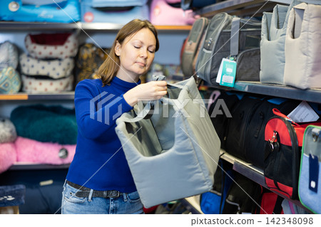 Woman choosing fabric pet carrier bag for cats in pet shop Woman choosing fabric pet carrier bag for cats in pet shop 142348098