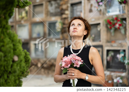 Woman brought flowers to the cemetery and cries over the death of beloved relative Woman brought flowers to the cemetery and cries over the death of beloved relative 142348225