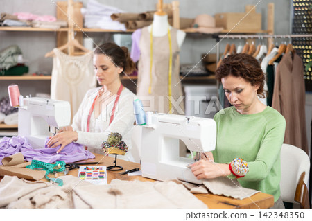 Two women tailor at work in cloth design shop. Two women tailor at work in cloth design shop. 142348350