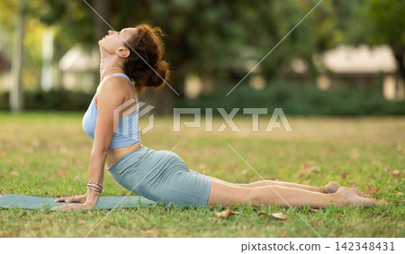 Adult woman doing yoga in cobra pose Adult woman doing yoga in cobra pose 142348431