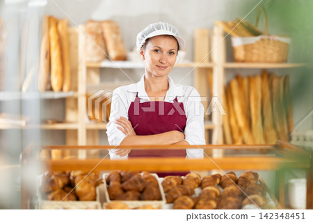 Female baker worker sells croissants, shows many different crescent rolls Female baker worker sells croissants, shows many different crescent rolls 142348451