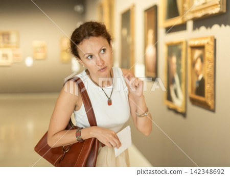 Woman viewing art gallery with brochure Woman viewing art gallery with brochure 142348692