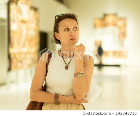 Woman viewing art gallery with brochure Woman viewing art gallery with brochure 142348716