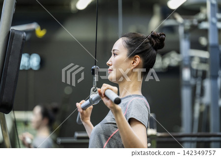 訓練:年輕女子,背闊肌下拉 訓練:年輕女子,背闊肌下拉 142349757