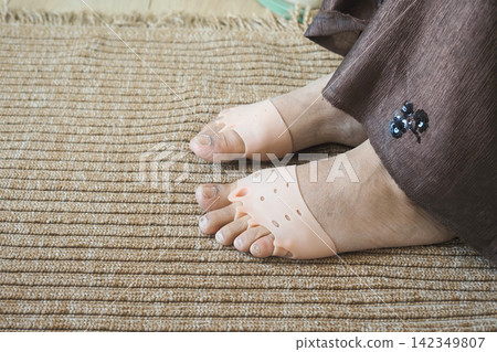 Feet are resting on a woven mat while wearing flesh-colored silicone gel sleeves, Feet are resting on a woven mat while wearing flesh-colored silicone gel sleeves, 142349807