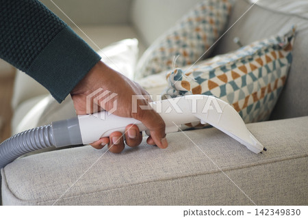 Vacuuming a couch in the living room 142349830