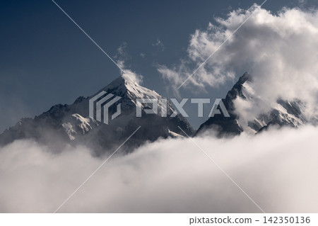 Snow Covered Mountain Peaks Rising Above Thick White Clouds Snow Covered Mountain Peaks Rising Above Thick White Clouds 142350136