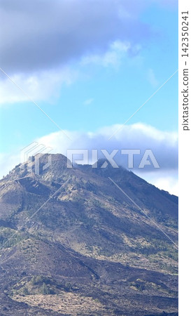 Rugged volcanic mountain ridge under blue sky with low clouds, tourist destination ,ridge, rocky detail, showing lava, slope, summit, peak context, with clear visible detail Rugged volcanic mountain ridge under blue sky with low clouds, tourist destination ,ridge, rocky detail, showing lava, slope, summit, peak context, with clear visible detail 142350241