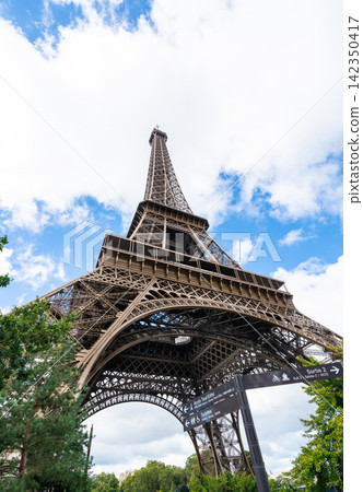 Low angle view of eiffel tower framed by green trees under blue sky in paris france Low angle view of eiffel tower framed by green trees under blue sky in paris france 142350417
