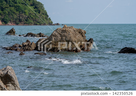 Rugged coastal rock formation surrounded by rolling seawater along a tropical shoreline in Thailand. Natural erosion, geology and an unspoiled marine landscape. Travel and coastal environment themes. Rugged coastal rock formation surrounded by rolling seawater along a tropical shoreline in Thailand. Natural erosion, geology and an unspoiled marine landscape. Travel and coastal environment themes. 142350526