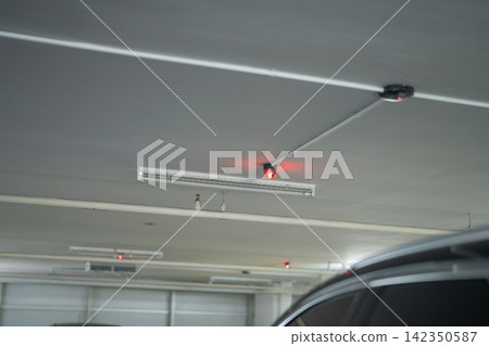 Smart parking guidance system with illuminated red sensors above parked cars. Automated space detection, parking management and efficient urban mobility. Smart parking space monitoring technology. Smart parking guidance system with illuminated red sensors above parked cars. Automated space detection, parking management and efficient urban mobility. Smart parking space monitoring technology. 142350587