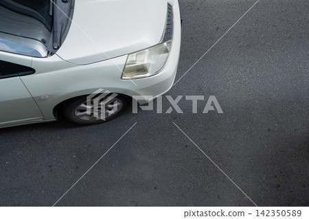 White car on dark asphalt road. Urban transportation. Private vehicle, mobility and road surface for advertising, insurance or automotive design. Road safety. Car service, driving, mobility. White car on dark asphalt road. Urban transportation. Private vehicle, mobility and road surface for advertising, insurance or automotive design. Road safety. Car service, driving, mobility. 142350589
