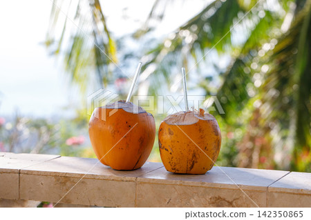 Two Fresh Coconuts on Tropical Beach with Palm Leaves and Sea Background 142350865