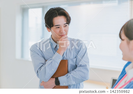 A businessman ponders how to win over a female colleague he likes, his hand on his chin. A businessman ponders how to win over a female colleague he likes, his hand on his chin. 142350982