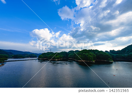Vast lake surface and summer sky above; Nunome Dam; 12mm; blank copy space at the top; horizontal composition; clouds on the right of the sky; suitable for B0 poster. Vast lake surface and summer sky above; Nunome Dam; 12mm; blank copy space at the top; horizontal composition; clouds on the right of the sky; suitable for B0 poster. 142351565