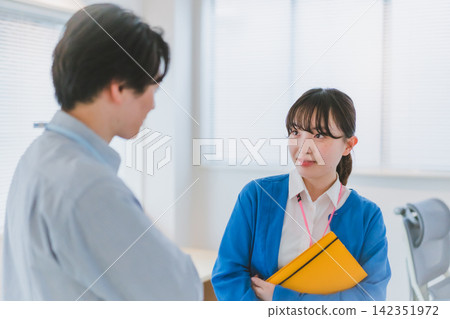 一名女員工拿著筆記本,注視著一位男同事,並對他產生了感情──一段辦公室戀情。 一名女員工拿著筆記本,注視著一位男同事,並對他產生了感情──一段辦公室戀情。 142351972