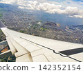 The view of the blue sky and the wing from the airplane window. 142352154