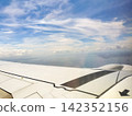 The view of the blue sky and the wing from the airplane window. 142352156