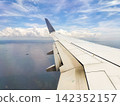 The view of the blue sky and the wing from the airplane window. 142352157