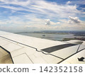 The view of the blue sky and the wing from the airplane window. 142352158