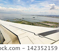 The view of the blue sky and the wing from the airplane window. 142352159