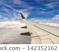 The view of the blue sky and the wing from the airplane window. 142352162