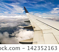 The view of the blue sky and the wing from the airplane window. 142352163