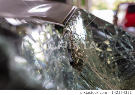 Closeup of severely shattered car windshield broken safety glass impact damage showing the aftermath of vehicle accident need for repair Closeup of severely shattered car windshield broken safety glass impact damage showing the aftermath of vehicle accident need for repair 142354351