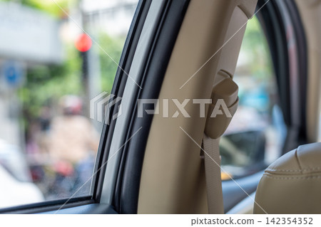 Closeup of car seat belt mounted the interior pillar beside passenger window highlighting vehicle safety restraint modern automotive cabin design Closeup of car seat belt mounted the interior pillar beside passenger window highlighting vehicle safety restraint modern automotive cabin design 142354352