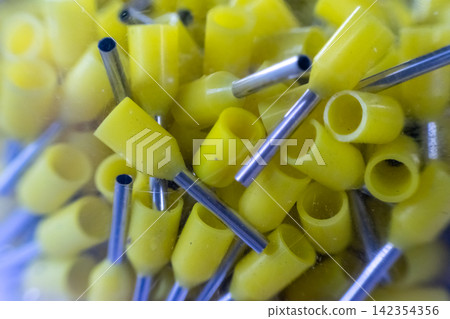 Closeup of yellow insulated wire ferrules metal tubes grouped together for electrical wiring connection installation repair industrial assembly Closeup of yellow insulated wire ferrules metal tubes grouped together for electrical wiring connection installation repair industrial assembly 142354356