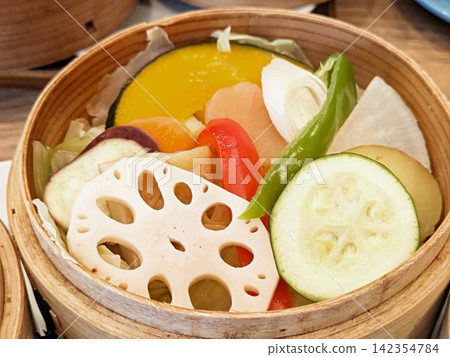 A platter of fresh, colorful steamed vegetables, perfectly arranged in a bamboo basket. A platter of fresh, colorful steamed vegetables, perfectly arranged in a bamboo basket. 142354784