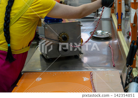 Confectioner Using Automatic Candy Sizer Machine to Shape Small Sweets Confectioner Using Automatic Candy Sizer Machine to Shape Small Sweets 142354851