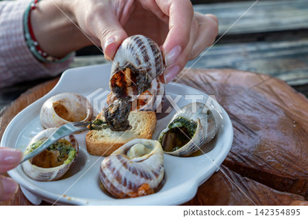 Macro Shot of Person Extracting Cooked Escargot from Shell with Fork Macro Shot of Person Extracting Cooked Escargot from Shell with Fork 142354895