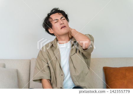 A middle-aged man suffering from neck and shoulder pain, clutching his neck; image of stiff shoulders and fatigue. A middle-aged man suffering from neck and shoulder pain, clutching his neck; image of stiff shoulders and fatigue. 142355779