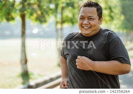overweight man with a smile while jogging in the morning overweight man with a smile while jogging in the morning 142356264