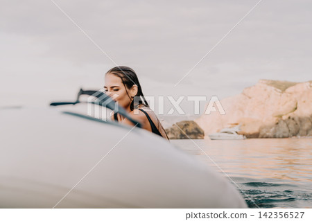 Woman, Surfboard, Water - Young woman with wet hair sits on a surfboard in the ocean. Woman, Surfboard, Water - Young woman with wet hair sits on a surfboard in the ocean. 142356527