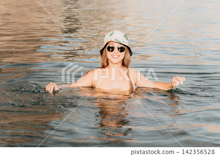 Woman, Water, Sunglasses - Smiling woman in sunglasses swims in water with a hat on her head. Woman, Water, Sunglasses - Smiling woman in sunglasses swims in water with a hat on her head. 142356528