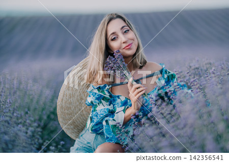 Lavender field woman smiling in a purple flower meadow with straw hat and floral top enjoying summer sunset Lavender field woman smiling in a purple flower meadow with straw hat and floral top enjoying summer sunset 142356541