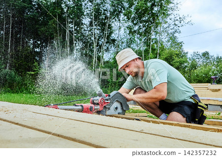Plunge saw works from mains power while cutting wooden boards with adjustable depth and bevel angle, directing sawdust sideways during precise guided sawing. 142357232