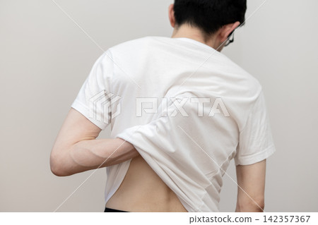 中年男子的背影,顯示他因痱子導致皮膚乾燥、背部搔癢。 中年男子的背影,顯示他因痱子導致皮膚乾燥、背部搔癢。 142357367