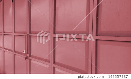Red metal folding garage door with a geometric panel design. Red metal folding garage door with a geometric panel design. 142357387