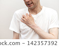 A middle-aged man winces in pain from the itching on his chest caused by dry skin and heat rash. 142357392