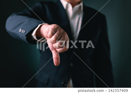 Businessman hand showing thumb down sign. Concept of negative feedback, disapproval gesture, rejection symbol and bad review for business failure, crisis and disagreement. Businessman hand showing thumb down sign. Concept of negative feedback, disapproval gesture, rejection symbol and bad review for business failure, crisis and disagreement. 142357409