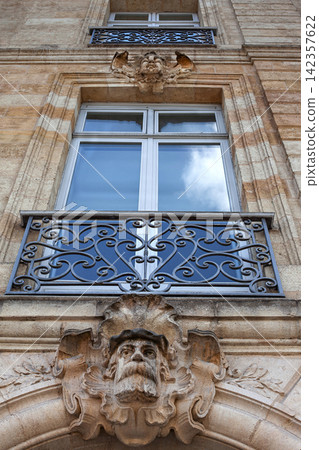 Wrought iron balcony and stone mascaron on a luxury French mansion Wrought iron balcony and stone mascaron on a luxury French mansion 142357622