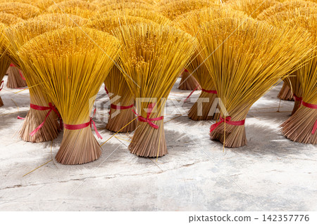 Bright yellow incense sticks bundled and tied with red ribbons Bright yellow incense sticks bundled and tied with red ribbons 142357776