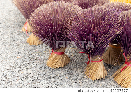Purple incense sticks bundled and tied with red ribbons Purple incense sticks bundled and tied with red ribbons 142357777
